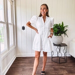 Fully lined white button down front dress with mock neck, V neck, short puffed sleeves, front pocket and elastic bands at the waist for a cinched waist look.