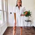 Fully lined white button down front dress with mock neck, V neck, short puffed sleeves, front pocket and elastic bands at the waist for a cinched waist look.