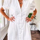 Fully lined white button down front dress with mock neck, V neck, short puffed sleeves, front pocket and elastic bands at the waist for a cinched waist look.