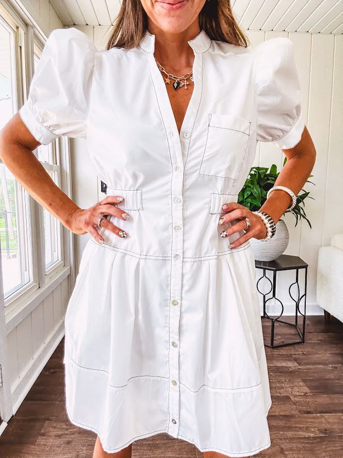 Fully lined white button down front dress with mock neck, V neck, short puffed sleeves, front pocket and elastic bands at the waist for a cinched waist look.