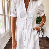 Fully lined white button down front dress with mock neck, V neck, short puffed sleeves, front pocket and elastic bands at the waist for a cinched waist look.