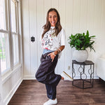 Black vinyl cargo pants with drawstring cuffs and cargo pockets topped with a denim waist band in a V shape with a button and zipper closure.
