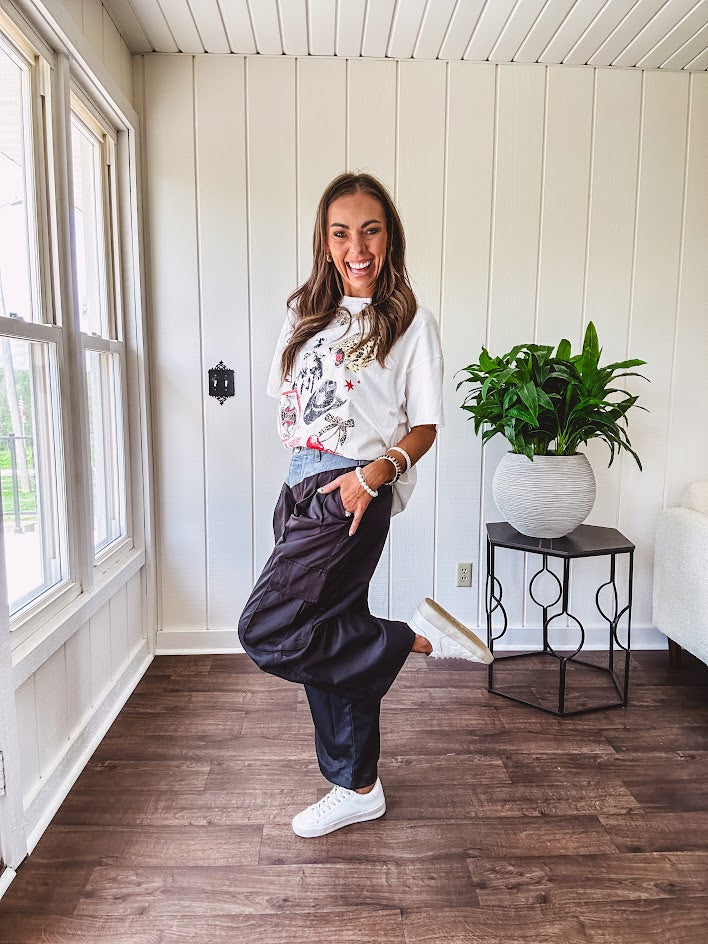 Black vinyl cargo pants with drawstring cuffs and cargo pockets topped with a denim waist band in a V shape with a button and zipper closure.