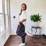 Black vinyl cargo pants with drawstring cuffs and cargo pockets topped with a denim waist band in a V shape with a button and zipper closure.