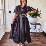 Black cotton maxi dress with white piping, collar, puff sleeve, scalloped hem, lined skirt and button down front.