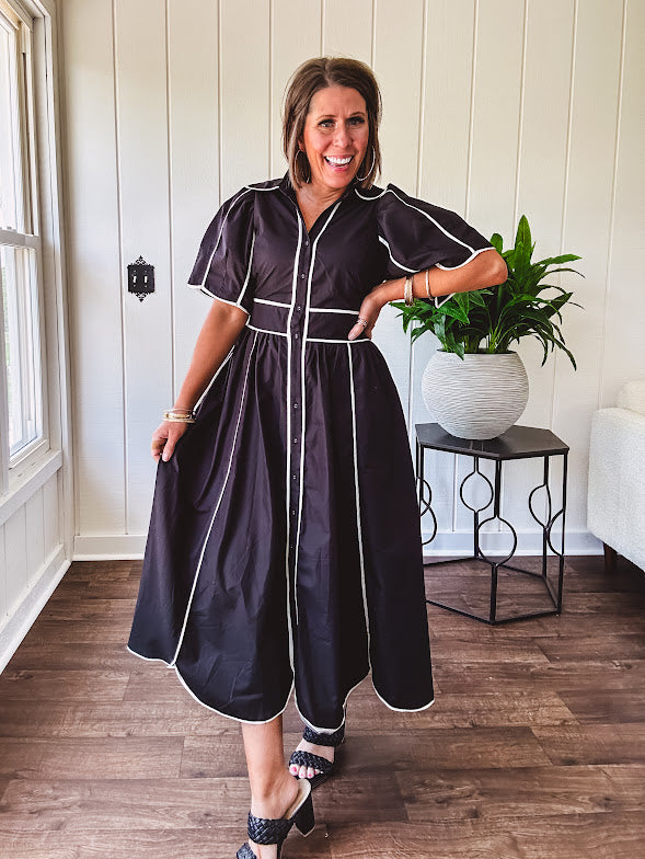 Black cotton maxi dress with white piping, collar, puff sleeve, scalloped hem, lined skirt and button down front.