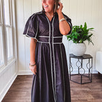 Black cotton maxi dress with white piping, collar, puff sleeve, scalloped hem, lined skirt and button down front.