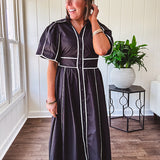 Black cotton maxi dress with white piping, collar, puff sleeve, scalloped hem, lined skirt and button down front.