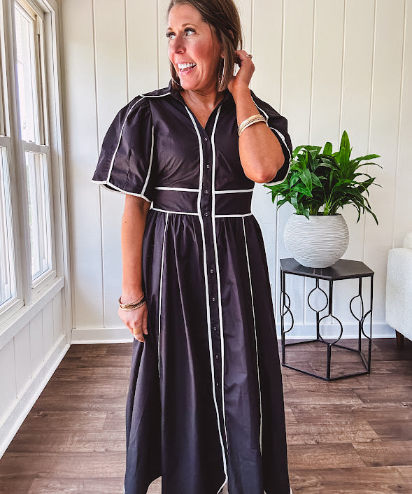Black cotton maxi dress with white piping, collar, puff sleeve, scalloped hem, lined skirt and button down front.