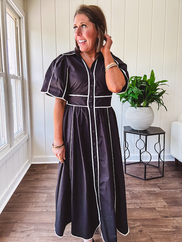 Black cotton maxi dress with white piping, collar, puff sleeve, scalloped hem, lined skirt and button down front.