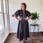 Black cotton maxi dress with white piping, collar, puff sleeve, scalloped hem, lined skirt and button down front.