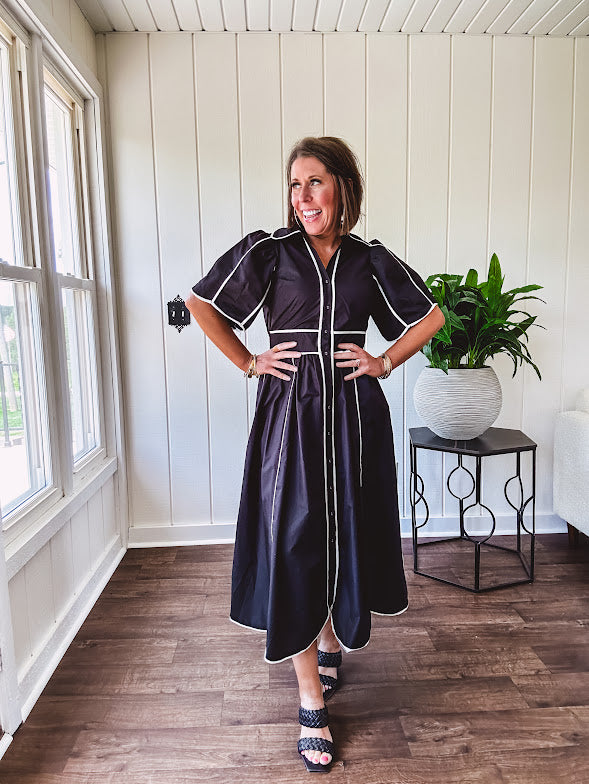 Black cotton maxi dress with white piping, collar, puff sleeve, scalloped hem, lined skirt and button down front.