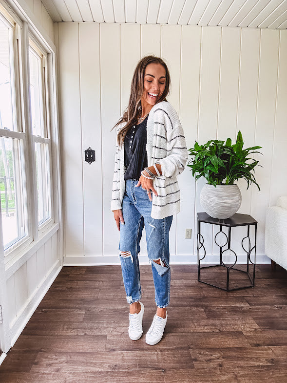 High rise stretch medium wash denim in a mom jean style with distressing at the knees and ankles, skinny design.