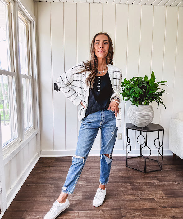 High rise stretch medium wash denim in a mom jean style with distressing at the knees and ankles, skinny design.