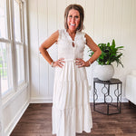 Oatmeal colored sleeveless midi dress with ruffled sleeves and collar with a tie, wide smocked bodice and lined, tiered skirt.