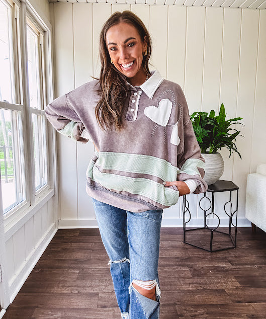 Washed terry knit slate grey pullover with white collar, and 3 snap button placket and heart patchwork and embroidery with Rugby style waffle texture striping detail and pockets.