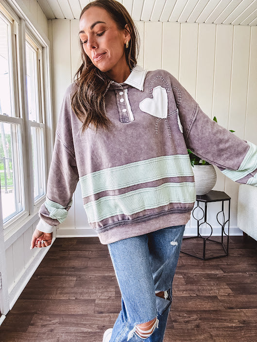 Washed terry knit slate grey pullover with white collar, and 3 snap button placket and heart patchwork and embroidery with Rugby style waffle texture striping detail and pockets.