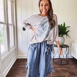 Light wash Tencel bloomer style pants with elastic, smocked waist band, front pockets with bow details and ruffled, angled hem.