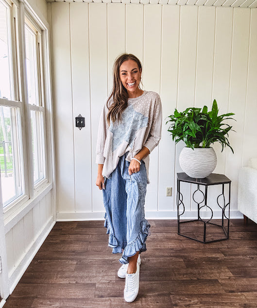 Light wash Tencel bloomer style pants with elastic, smocked waist band, front pockets with bow details and ruffled, angled hem.