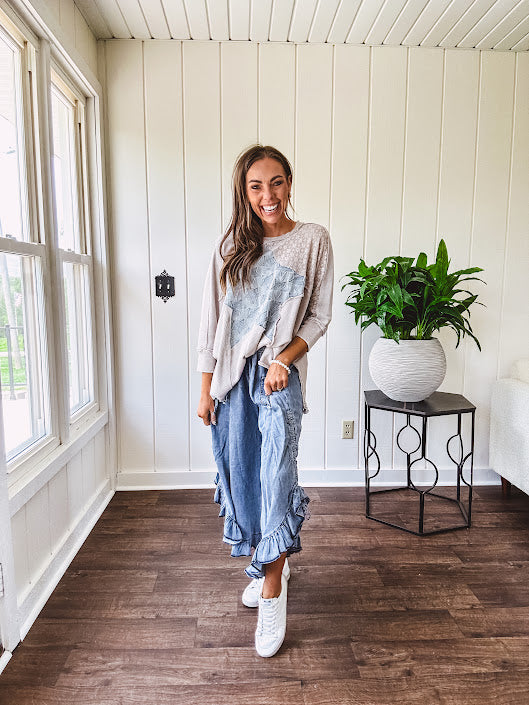 Light wash Tencel bloomer style pants with elastic, smocked waist band, front pockets with bow details and ruffled, angled hem.