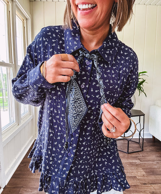 Navy gauze button down long sleeved top featuring a ruffled hem, front pocket and matching navy paisley scarf tie.
