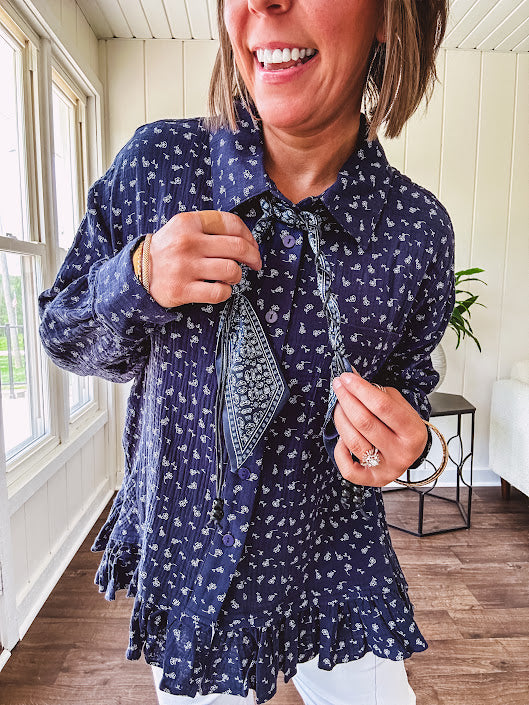 Navy gauze button down long sleeved top featuring a ruffled hem, front pocket and matching navy paisley scarf tie.
