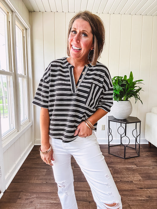 Black and white striped boxy cut Henley style knit top with 4 wooden buttons at the V neck, front pocket, short sleeves and shorter U shaped hem.