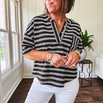Black and white striped boxy cut Henley style knit top with 4 wooden buttons at the V neck, front pocket, short sleeves and shorter U shaped hem.