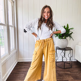 Washed mustard colored wide leg terry knit pants with a raw hem and elastic drawstring waist and oversized pockets.