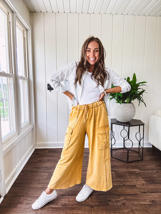 Washed mustard colored wide leg terry knit pants with a raw hem and elastic drawstring waist and oversized pockets.