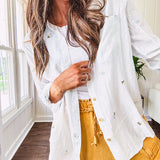 Thin, lightweight long sleeved button down blouse featuring white and blue or olive stripes adorned with small pastel floral embroidery throughout.