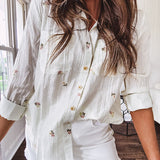 Thin, lightweight long sleeved button down blouse featuring white and blue or olive stripes adorned with small pastel floral embroidery throughout.