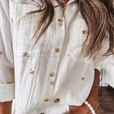 Thin, lightweight long sleeved button down blouse featuring white and blue or olive stripes adorned with small pastel floral embroidery throughout.