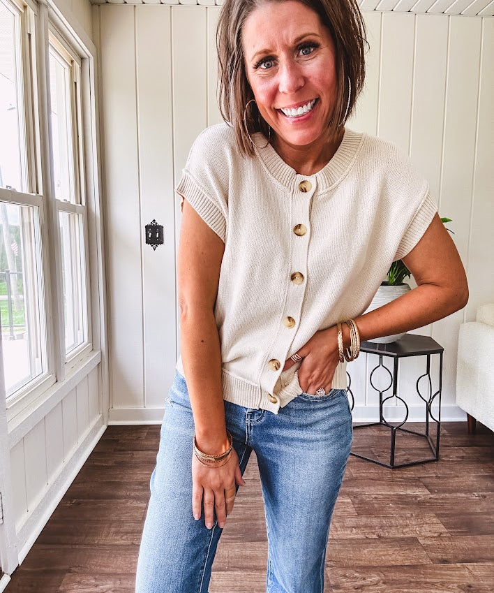 Soft, woven sweater vest with cap sleeves and faux wooden buttons down the front available in cream, sage and blush.