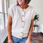 Soft, woven sweater vest with cap sleeves and faux wooden buttons down the front available in cream, sage and blush.