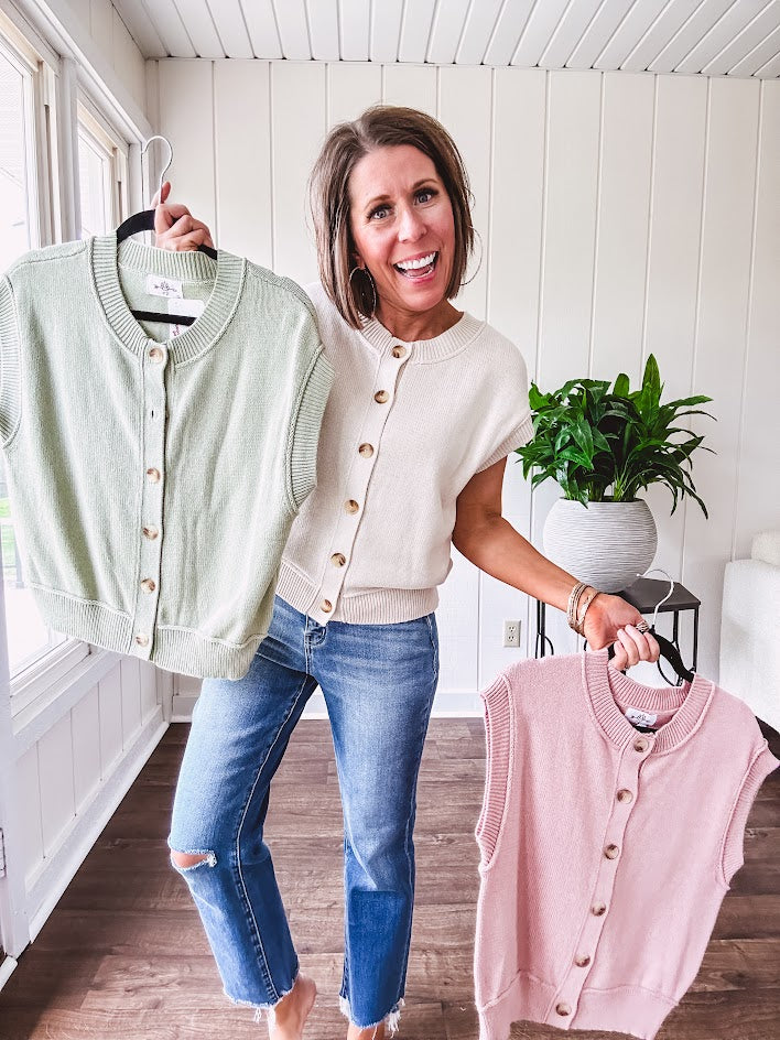 Soft, woven sweater vest with cap sleeves and faux wooden buttons down the front available in cream, sage and blush.