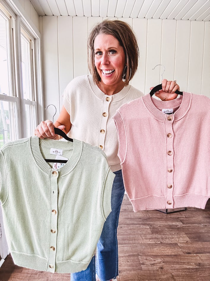 Soft, woven sweater vest with cap sleeves and faux wooden buttons down the front available in cream, sage and blush.