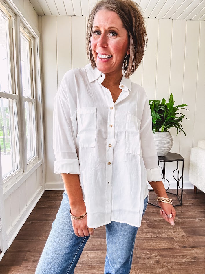 White, nearly sheer long sleeved button down with two front pockets, faux wooden buttons down the front and an oversized fit.