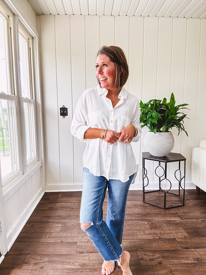 White, nearly sheer long sleeved button down with two front pockets, faux wooden buttons down the front and an oversized fit.