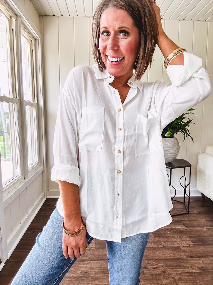White, nearly sheer long sleeved button down with two front pockets, faux wooden buttons down the front and an oversized fit.