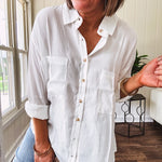 White, nearly sheer long sleeved button down with two front pockets, faux wooden buttons down the front and an oversized fit.