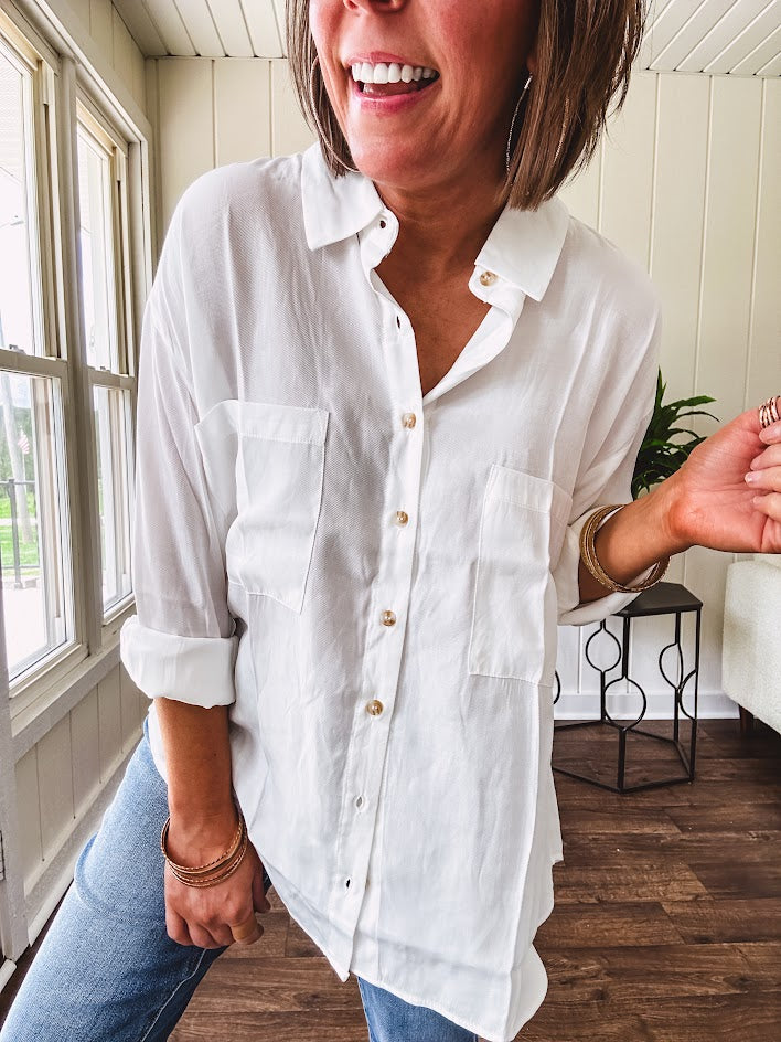 White, nearly sheer long sleeved button down with two front pockets, faux wooden buttons down the front and an oversized fit.