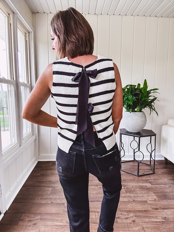 Soft black and white striped knit sweater vest with round neck and black bow ties at the back.