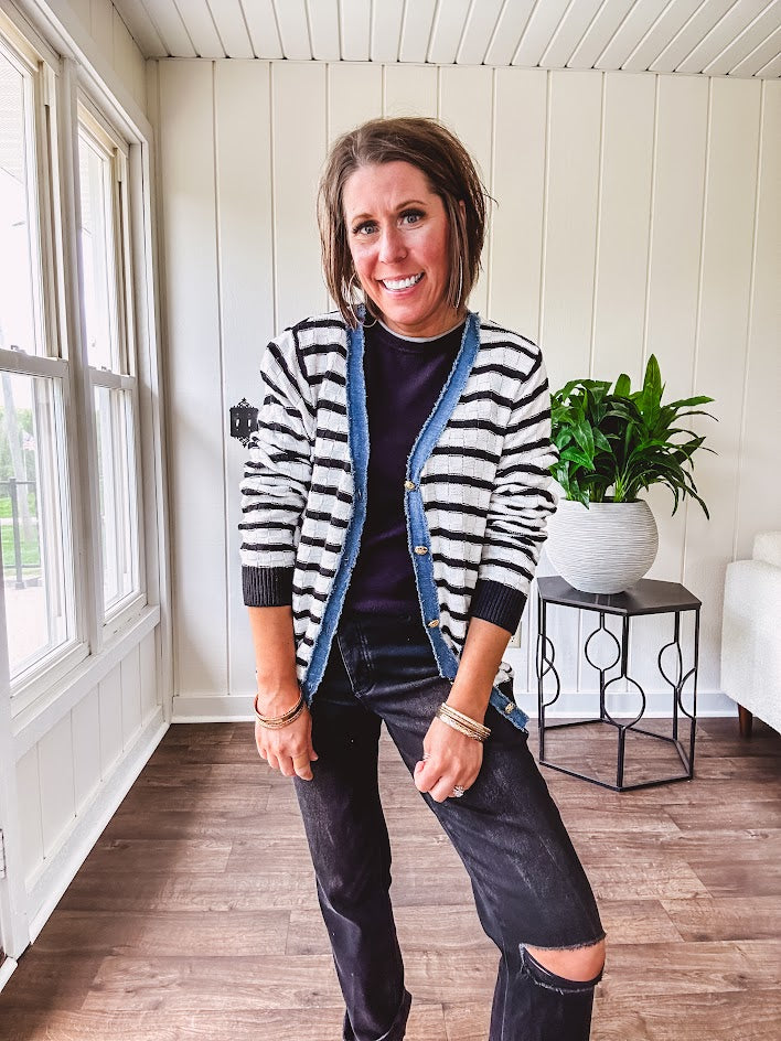 Lightweight black and white striped cardigan with checkered texture, denim raw edge trim at the placket and on the two faux front pockets with gold buttons.