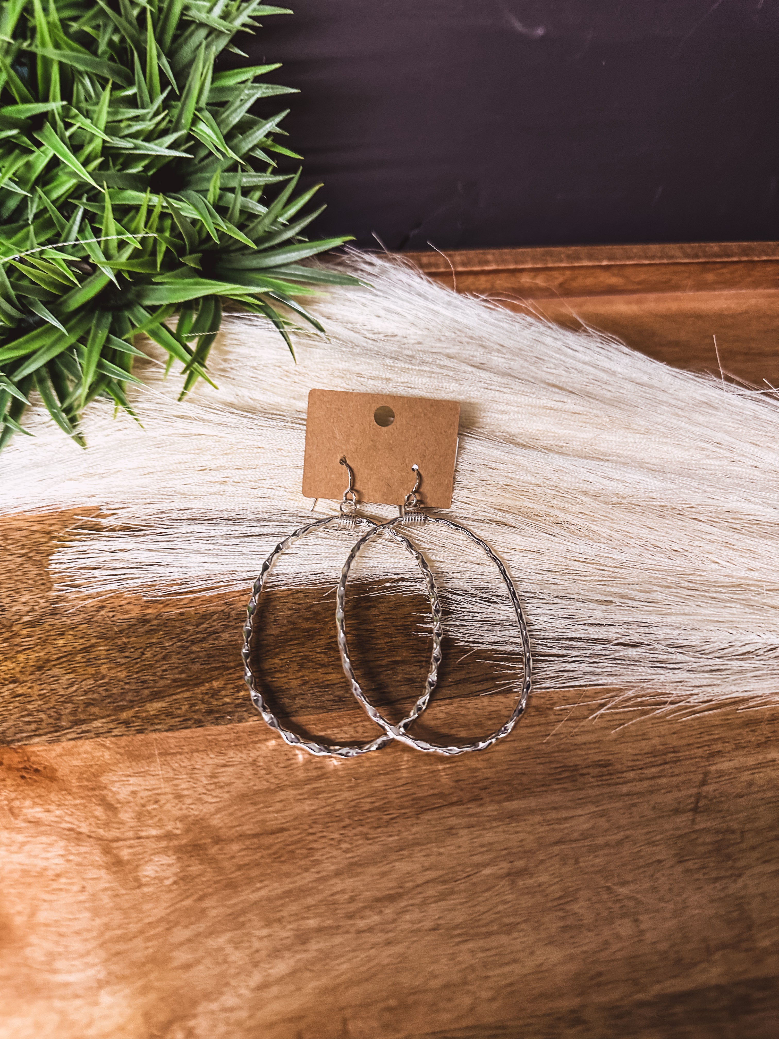 Large hammered sterling silver oval earrings on a shepherd's hook back.
