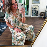 Lightweight and breezy set including a nearly sheer short sleeved tie front V neck top with cuffs at the sleeves and matching fully lined flowy skirt with elastic waist with flat front and pockets in beige with Earth toned tropical pattern.