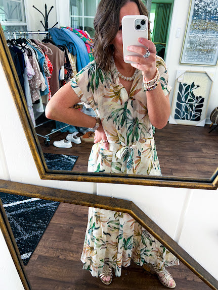 Lightweight and breezy set including a nearly sheer short sleeved tie front V neck top with cuffs at the sleeves and matching fully lined flowy skirt with elastic waist with flat front and pockets in beige with Earth toned tropical pattern.