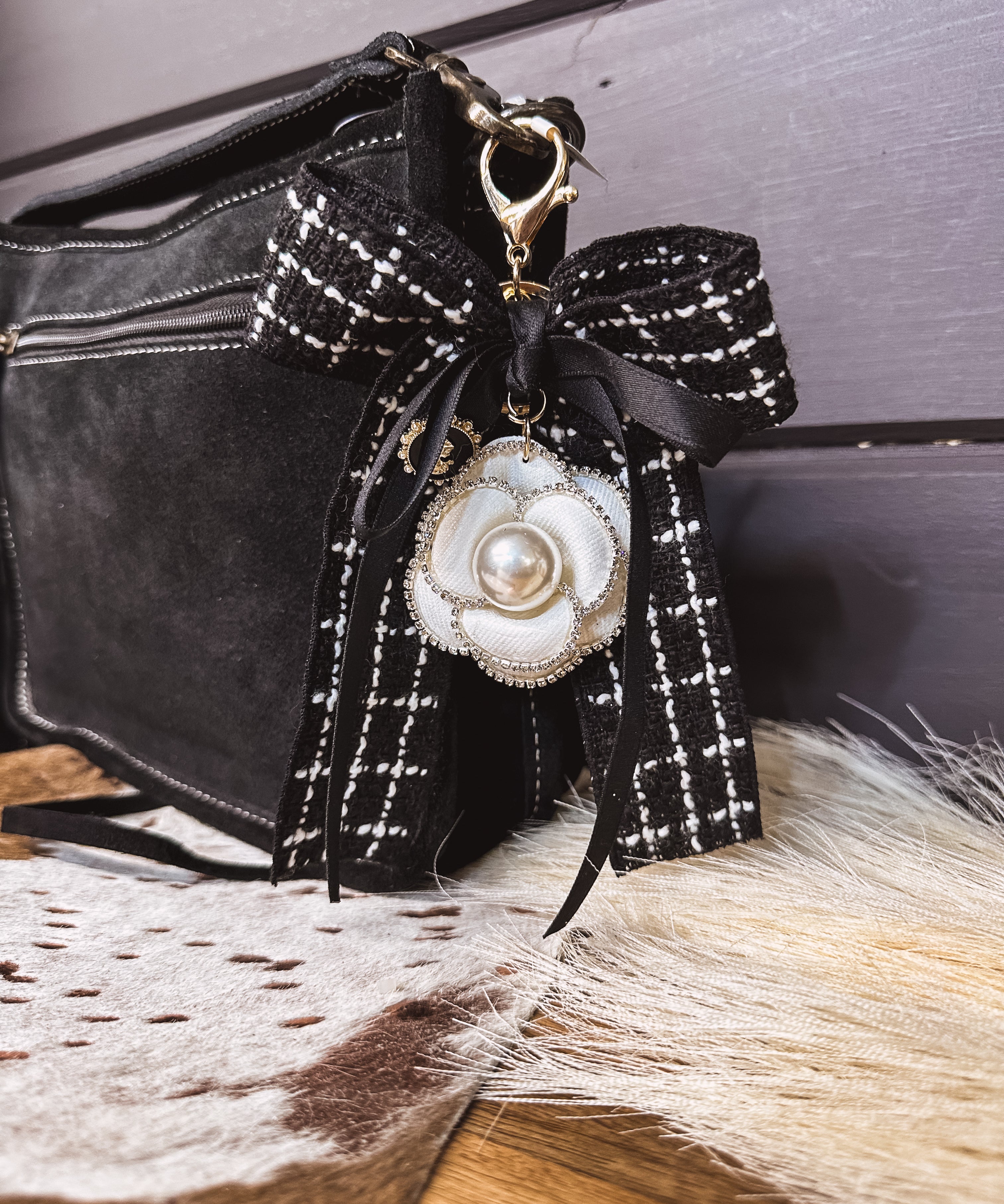 Black tweed fabric bow and black bow keychain with white floral and pearl charm on a lobster claw.