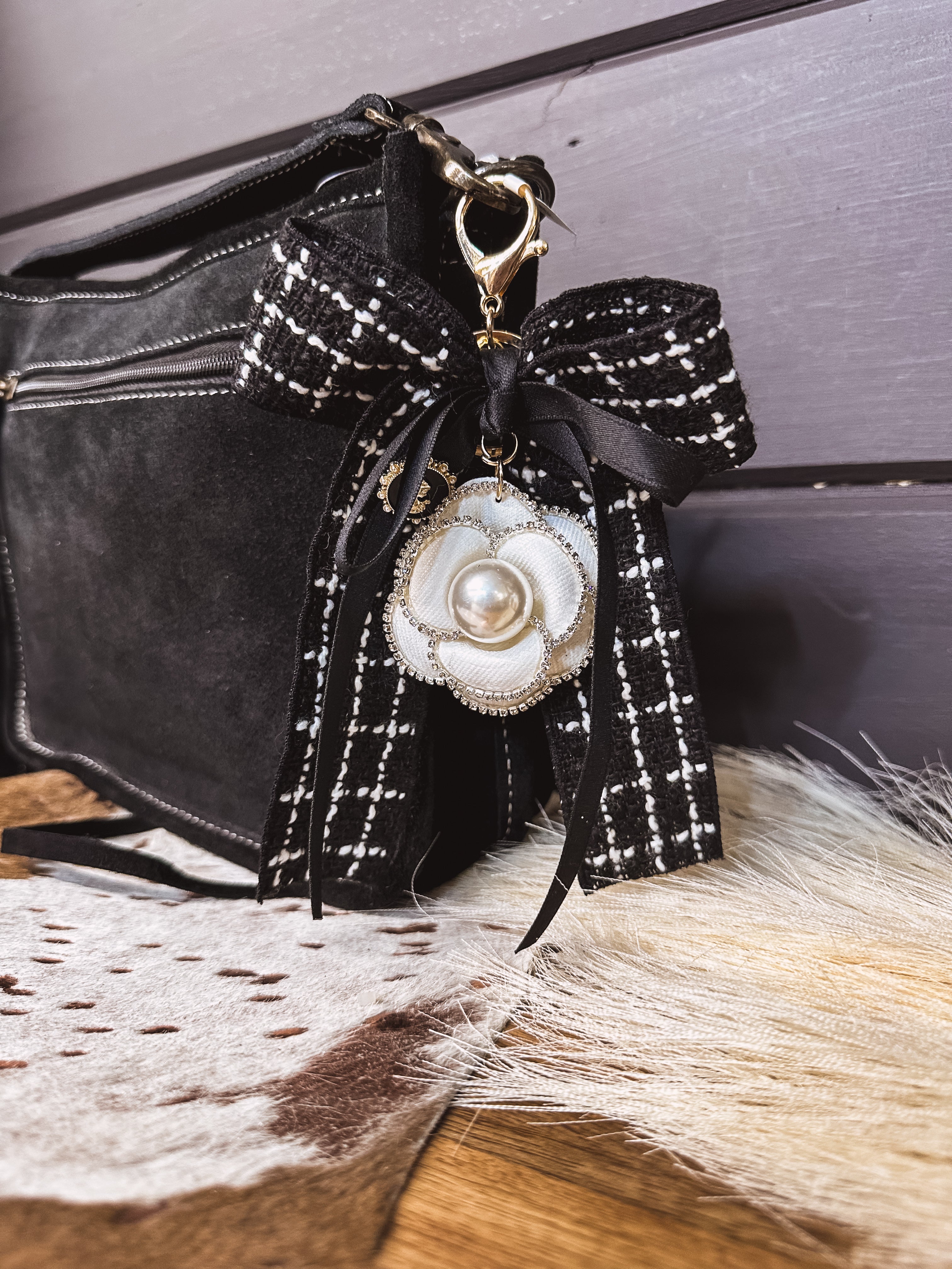 Black tweed fabric bow and black bow keychain with white floral and pearl charm on a lobster claw.