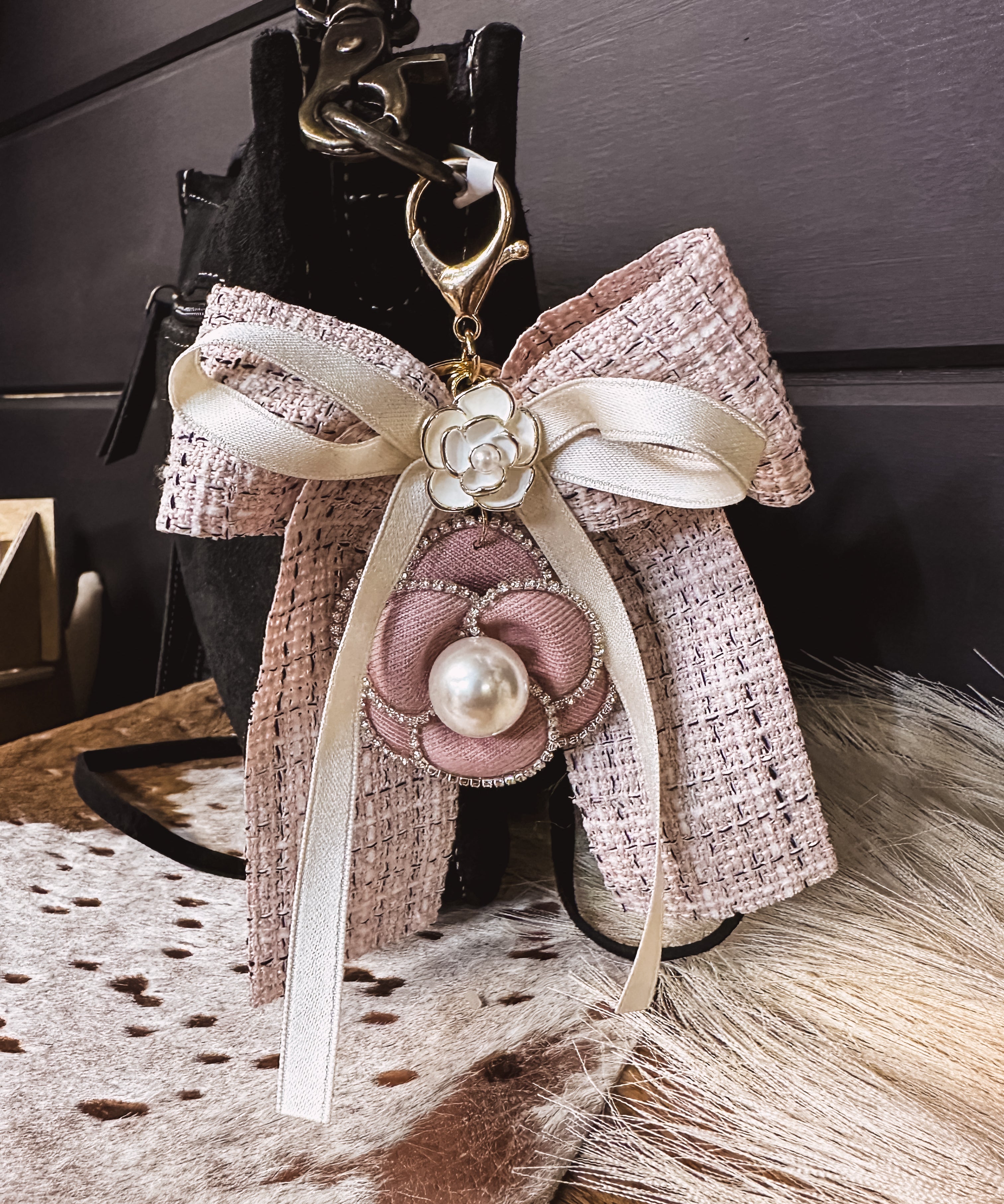 Pink tweed fabric bow and ivory bow keychain with pink and white floral and pearl charms on a lobster claw.